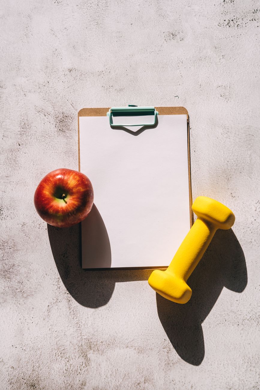 an apple and a dumbbell on a clipboard